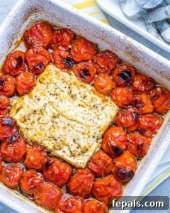 baked tomatoes and block of feta in a white dish