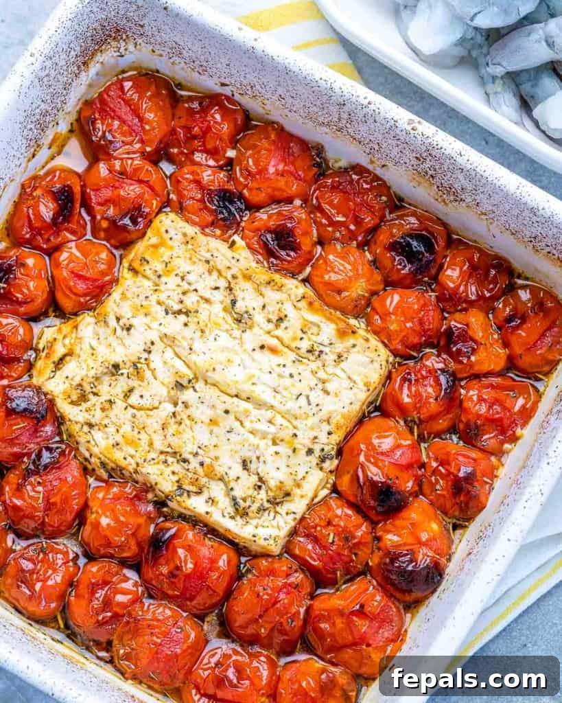 baked tomatoes and block of feta in a white dish