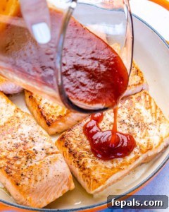 Fire-Kissed Salmon 13 BBQ sauce being drizzled over salmon fillets in a pan.