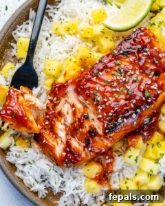 Fire-Kissed Salmon 14 A bowl of BBQ salmon served with rice and mango salsa (or pineapple), highlighting the finished dish.