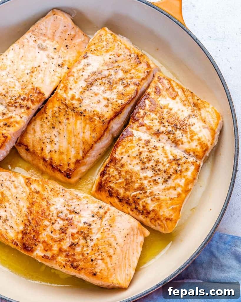 Fire-Kissed Salmon 6 Close-up view of two salmon fillets perfectly pan-seared to a golden brown in a non-stick pan.