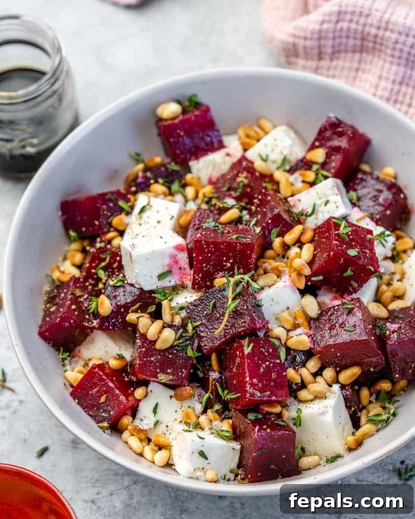 An overhead view of a colorful roasted beet salad, artfully arranged in a white bowl, highlighting its vibrant ingredients.
