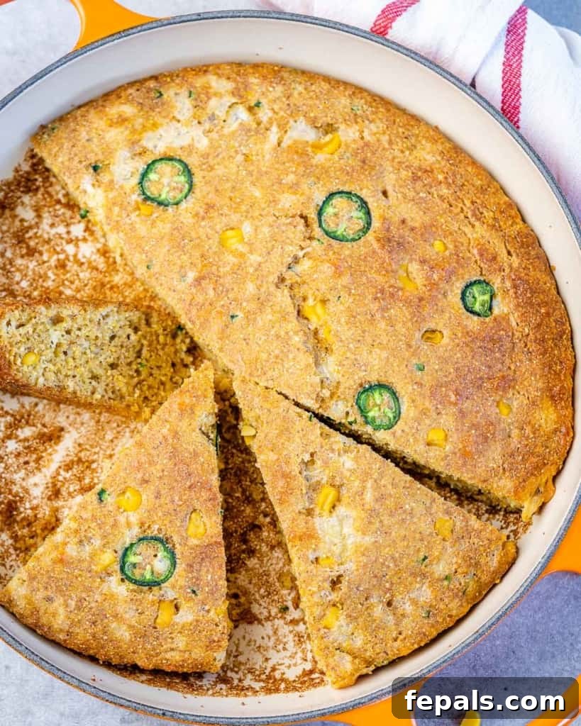 Top view of a freshly baked Jalapeño Skillet Cornbread in a cast iron skillet, golden brown with melted cheese and visible corn kernels.
