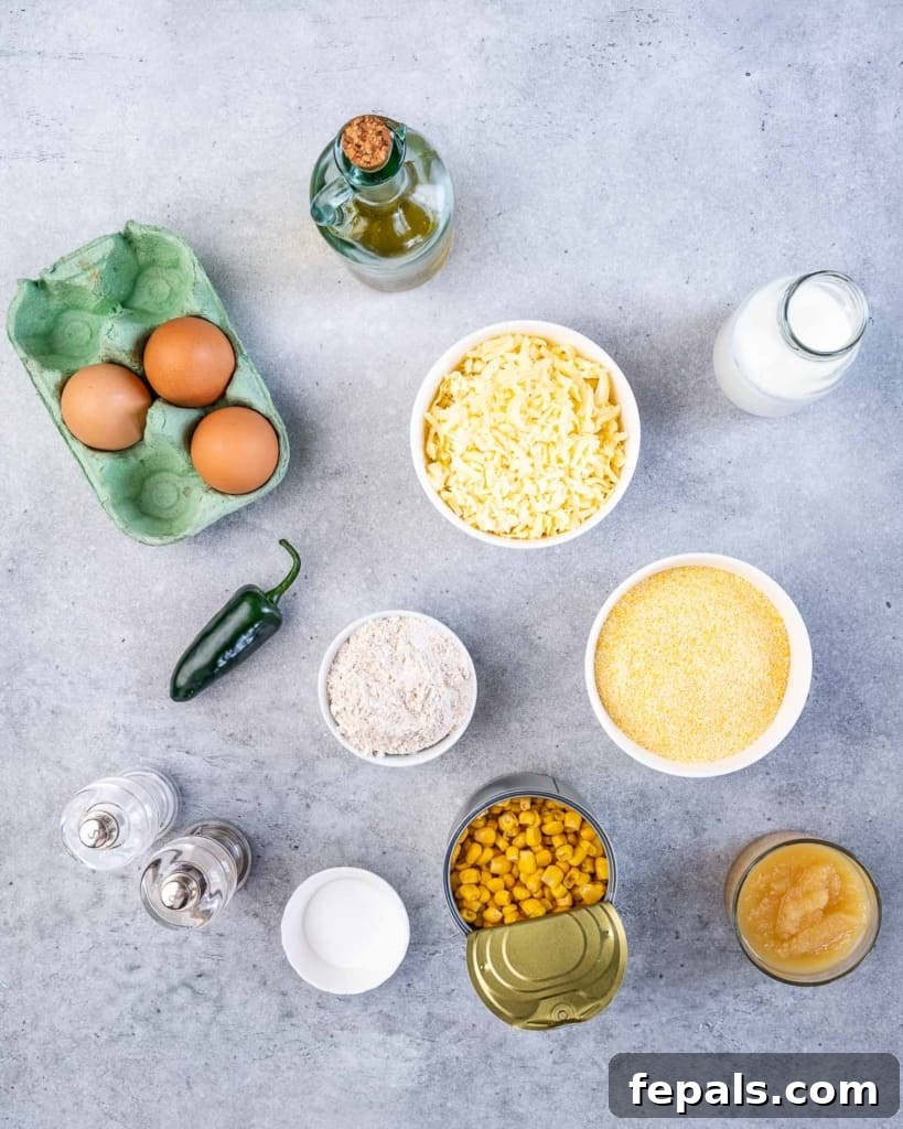 Individual bowls displaying the core ingredients: eggs, shredded cheese, flour, cornmeal, canned corn, buttermilk, olive oil, salt, fresh jalapeño, and baking powder.
