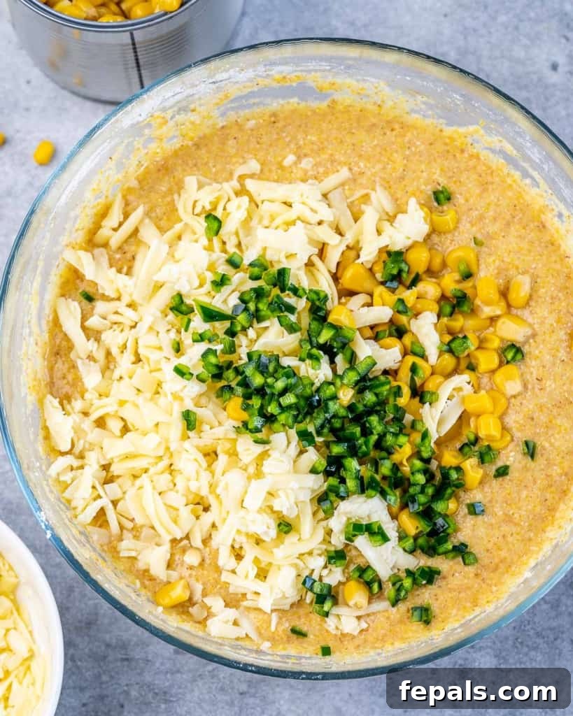 A mixing bowl filled with the vibrant batter for skillet cornbread, showing the mixture of cheese, corn, and jalapeño.