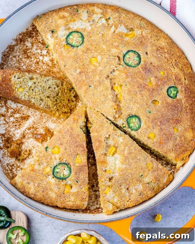 Top view of an entire Skillet Cornbread, generously topped with jalapeños and corn, still in the cast iron skillet.