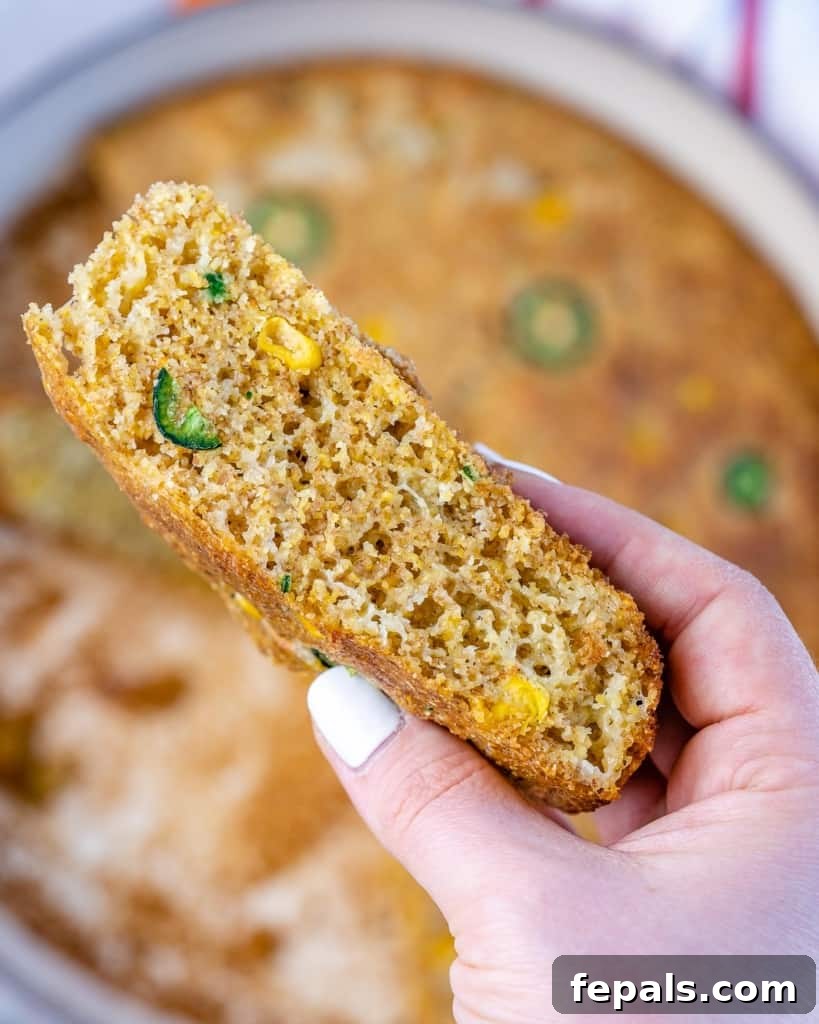 A single, inviting slice of Skillet Cornbread, showcasing its tender interior and flavorful additions.