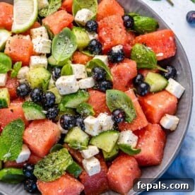 Top view of watermelon feta salad in bowl with lime wedges