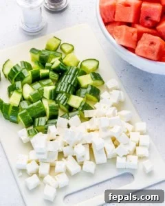 Cubed feta and watermelon with chopped cucumbers on cutting