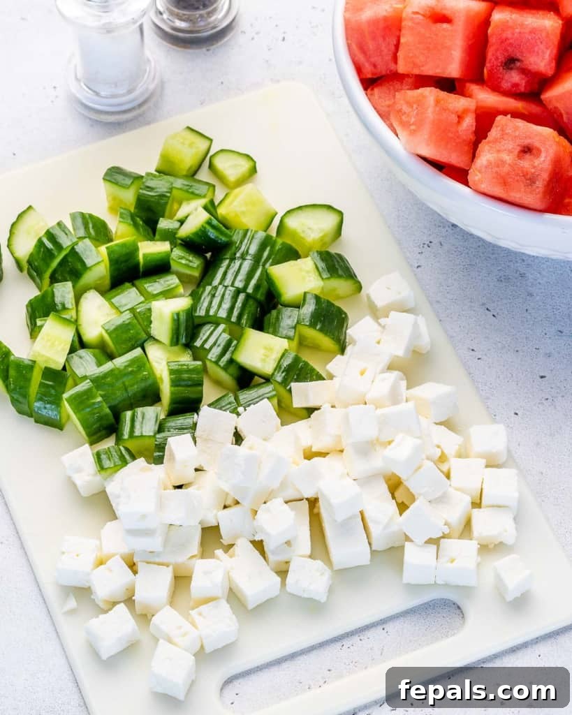 Vibrant Watermelon Feta Salad 5 Cubed feta and watermelon with chopped cucumbers on a cutting board, ready to be mixed for the salad.