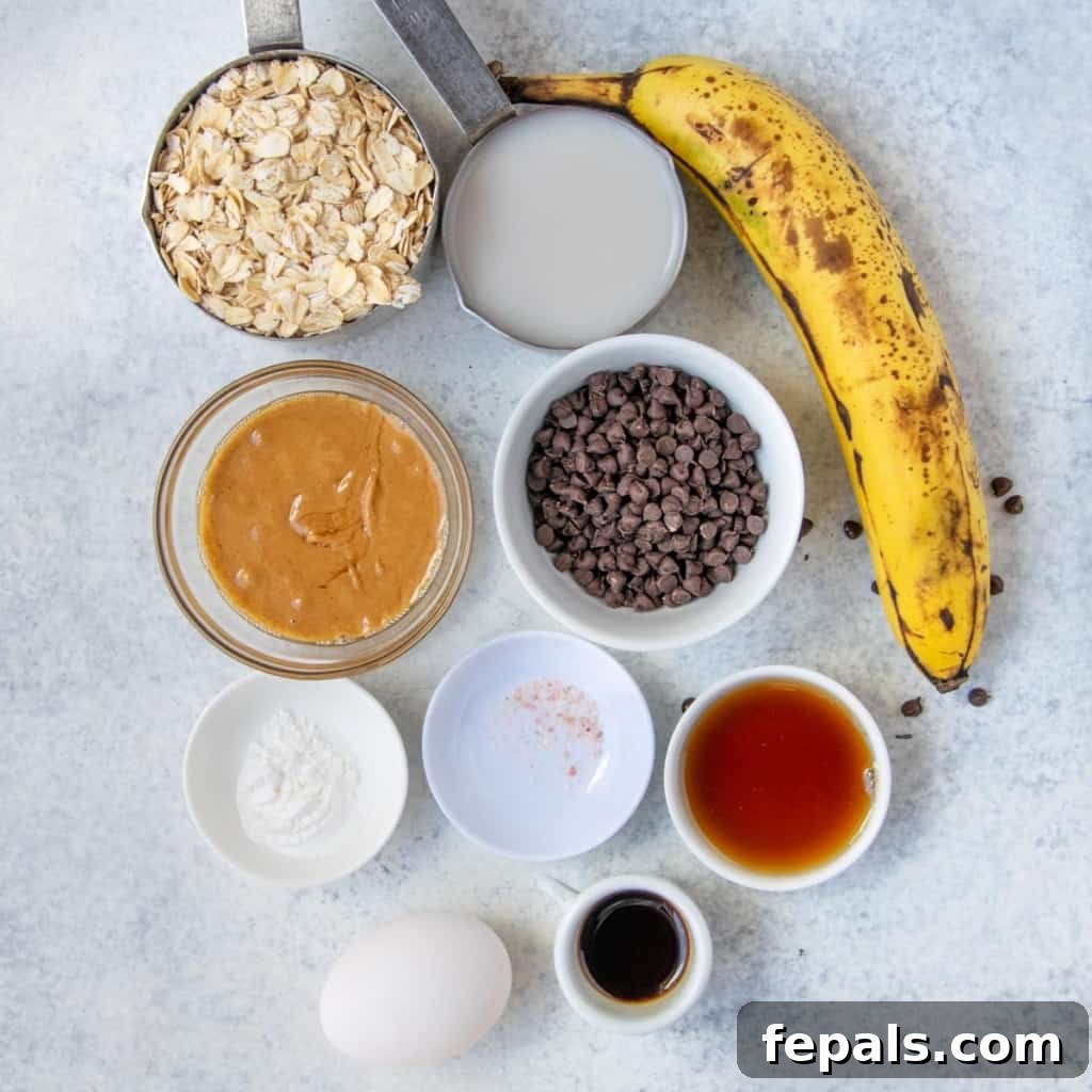 Chocolatey Baked Oatmeal Bliss 4 A flat lay of all the ingredients needed to make chocolate chip baked oats: oats, banana, milk, egg, vanilla, nut butter, maple syrup, baking soda, salt, and chocolate chips.