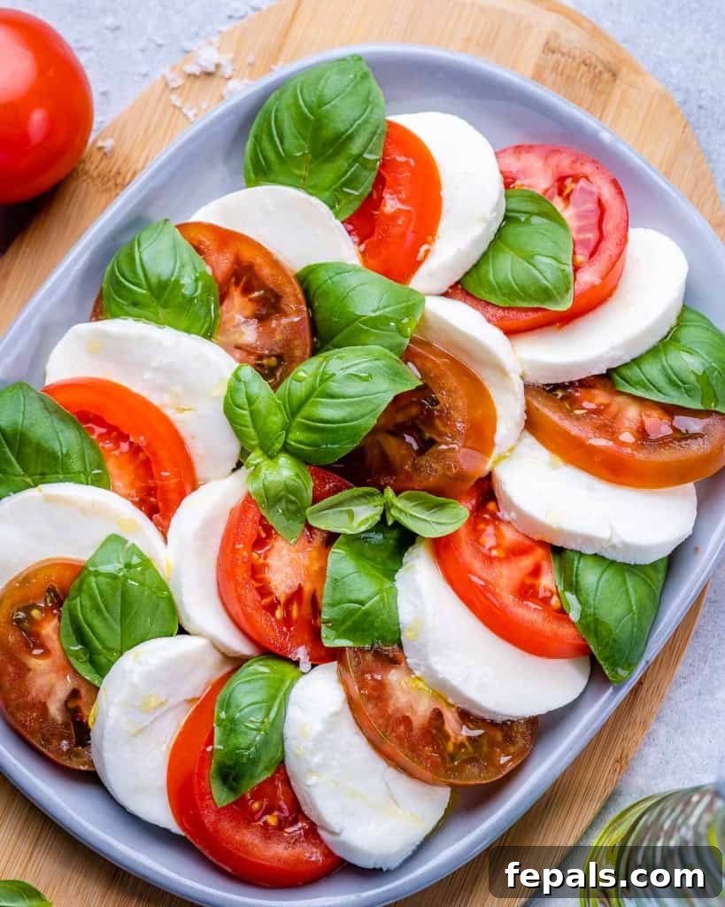 Effortless Caprese Perfection 6 A vibrant Caprese salad, perfectly layered with tomatoes, mozzarella, and basil, sits on a white plate, ready to be served.