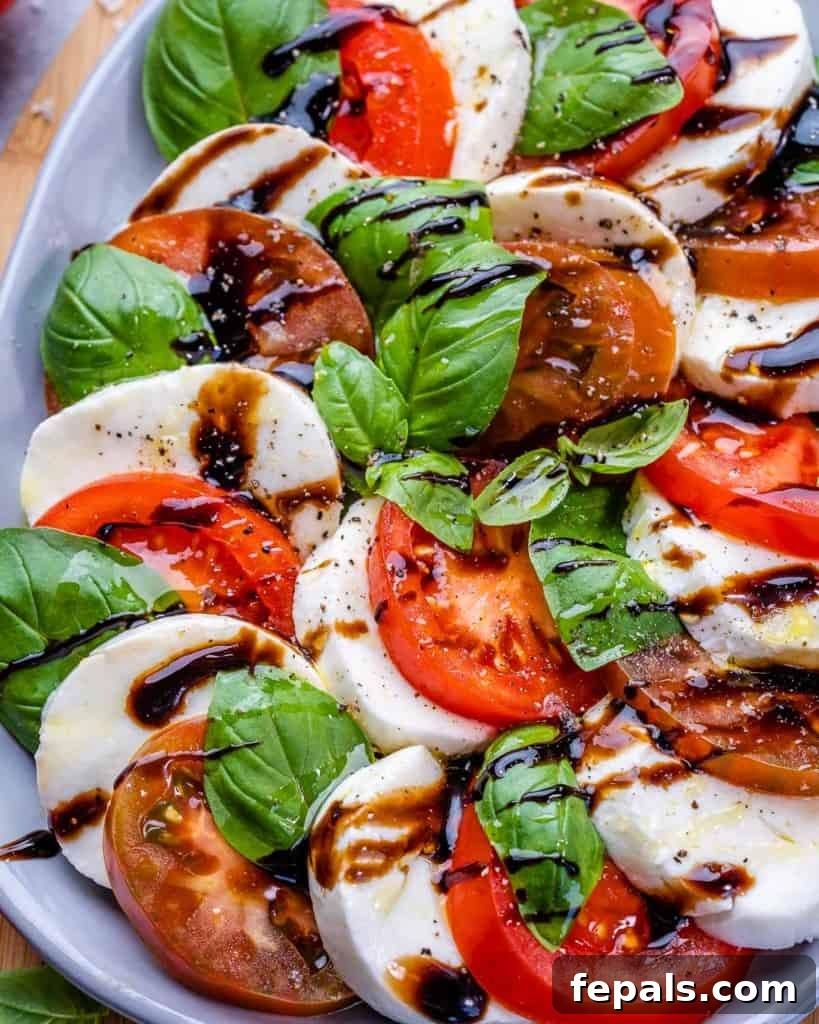 Effortless Caprese Perfection 7 Close-up image of a layered Caprese salad on a plate, featuring glistening balsamic drizzle and vibrant green basil leaves.