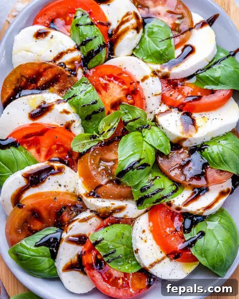 Effortless Caprese Perfection 8 Beautifully arranged Caprese salad on a white plate, adorned with a sweet balsamic drizzle and fresh basil leaves, ready to be enjoyed.
