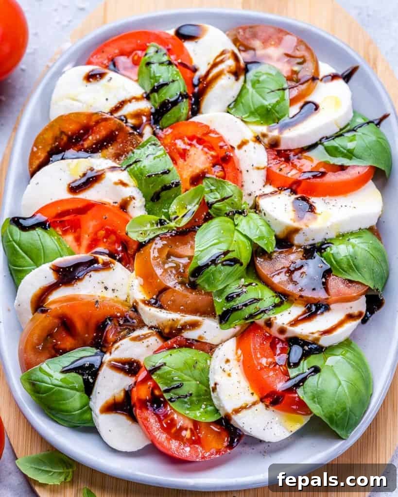 Effortless Caprese Perfection 10 Top view of a beautifully arranged Caprese salad on a plate, featuring a dark balsamic drizzle and fresh basil leaves, enhancing its appealing colors.