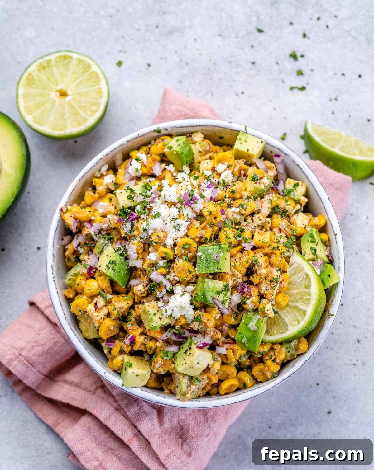Zesty Fiesta Corn Salad 6 A single bowl of Mexican street corn salad, garnished with a lime wedge and cilantro, ready to be enjoyed.
