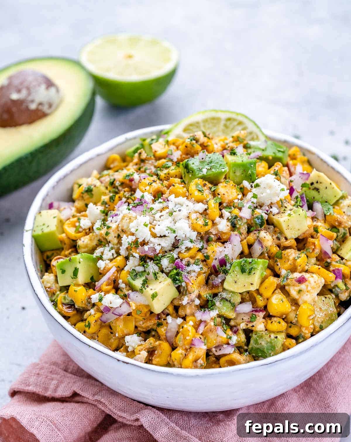 Zesty Fiesta Corn Salad 7 A second view of the Mexican street corn salad in a white bowl, with a pink napkin draped underneath.