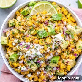 A bowl of Mexican street corn salad under a pink napkin, ready to be served.