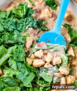 Spinach is added to the creamy chicken sauce in the pan.