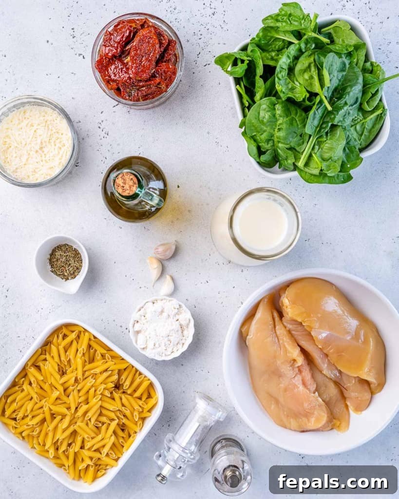 Various ingredients for Tuscan chicken pasta laid out on a wooden board, including chicken, pasta, spinach, sun-dried tomatoes, and spices.