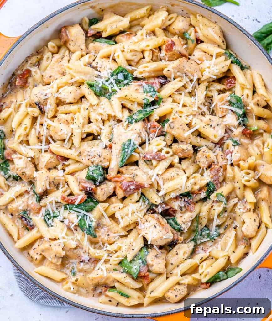 Top-down view of creamy chicken pasta in a pan, garnished with herbs.