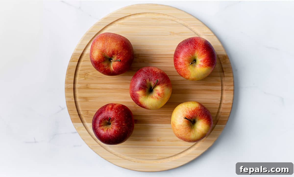 Best Way to Cut an Apple Fast five whole apples on a wooden cutting board, ready for slicing