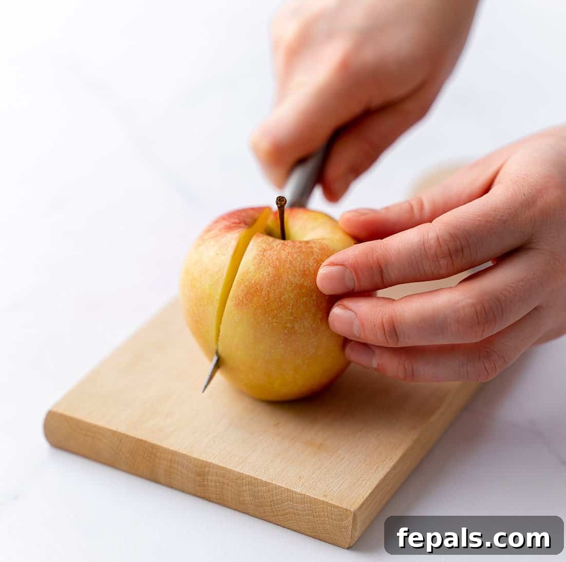 Precise Apple Slicing Technique side shot of hand slicing apple with knife, demonstrating the first cut alongside the core