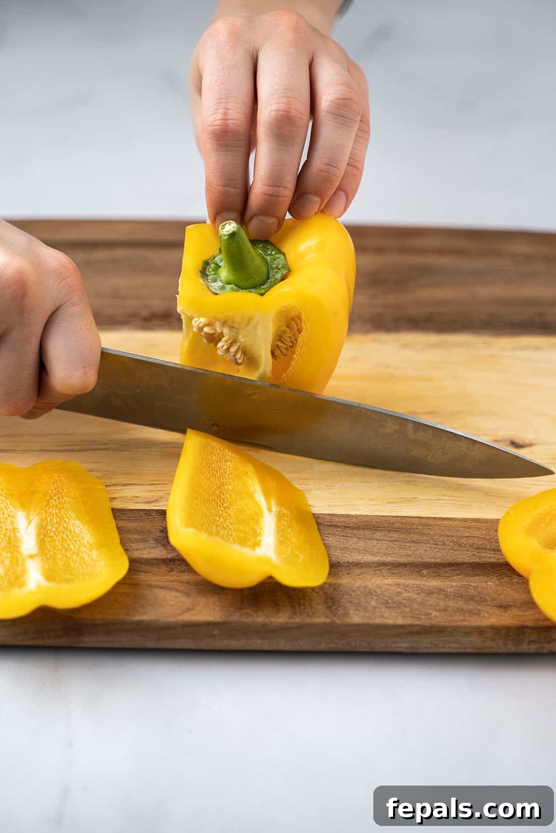 Master Bell Pepper Cutting Three Ways 13 Demonstration of slicing off another side of the yellow bell pepper, preparing for dicing.