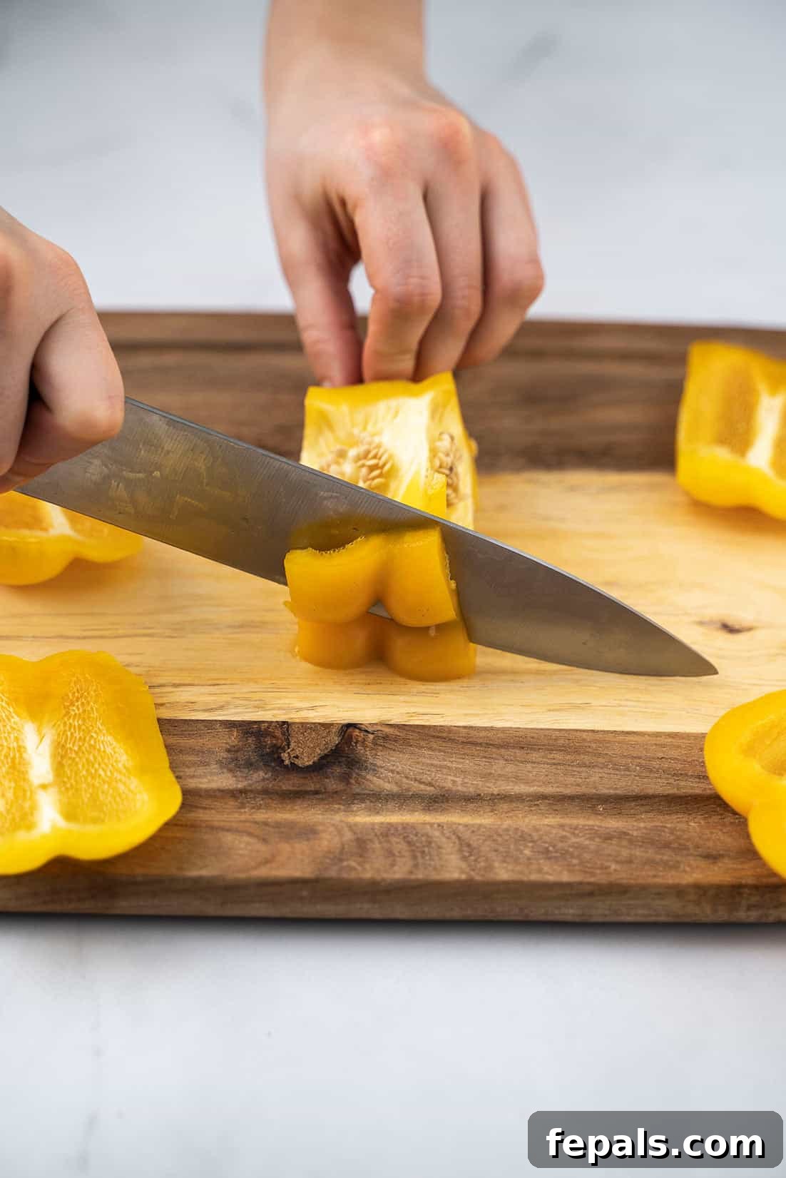 Master Bell Pepper Cutting Three Ways 15 A knife making a clean cut across a bell pepper section, preparing it for uniform dicing.