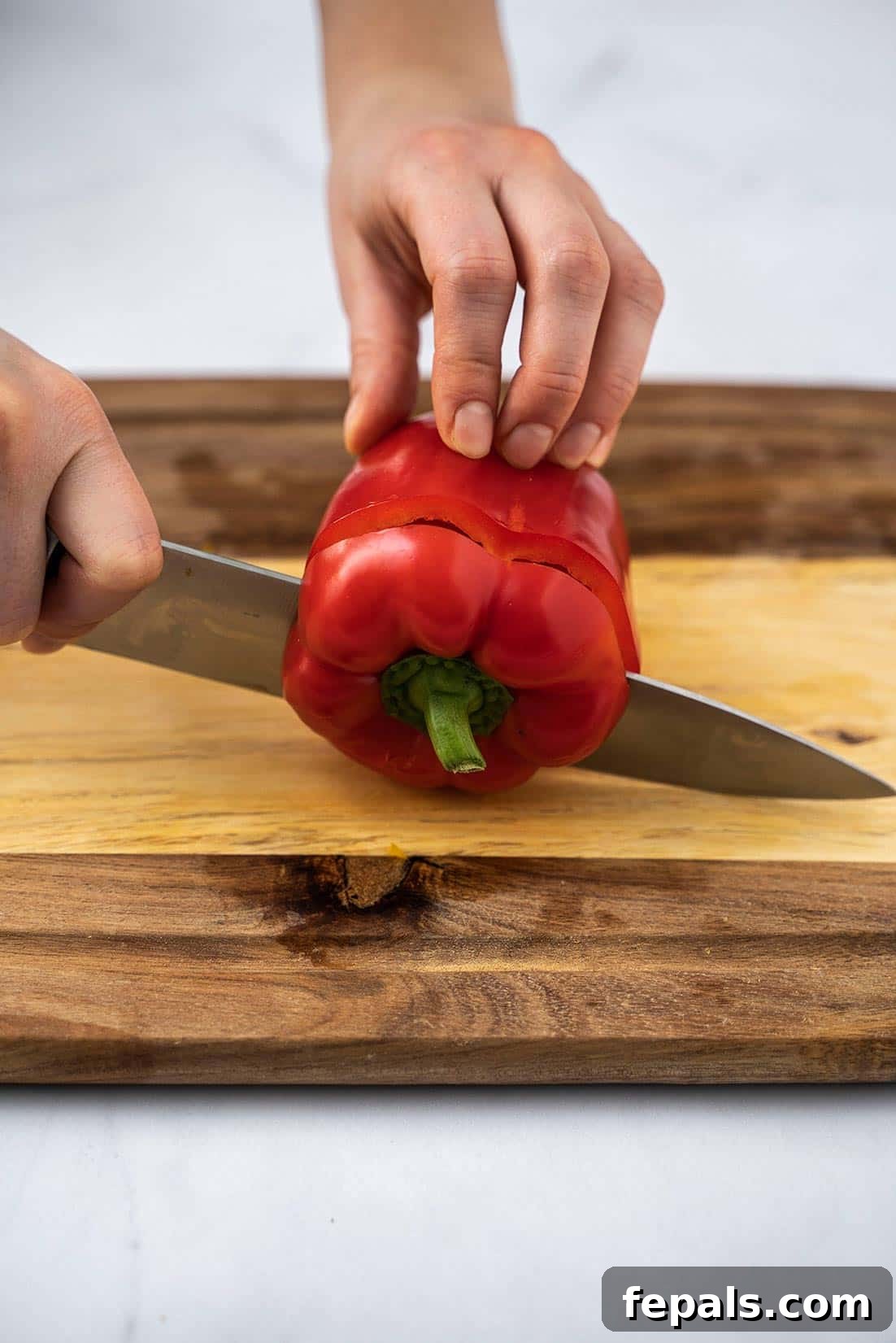 Master Bell Pepper Cutting Three Ways 19 Precise cut removing the top of a bell pepper to prepare it for ring slicing, showing the internal structure.