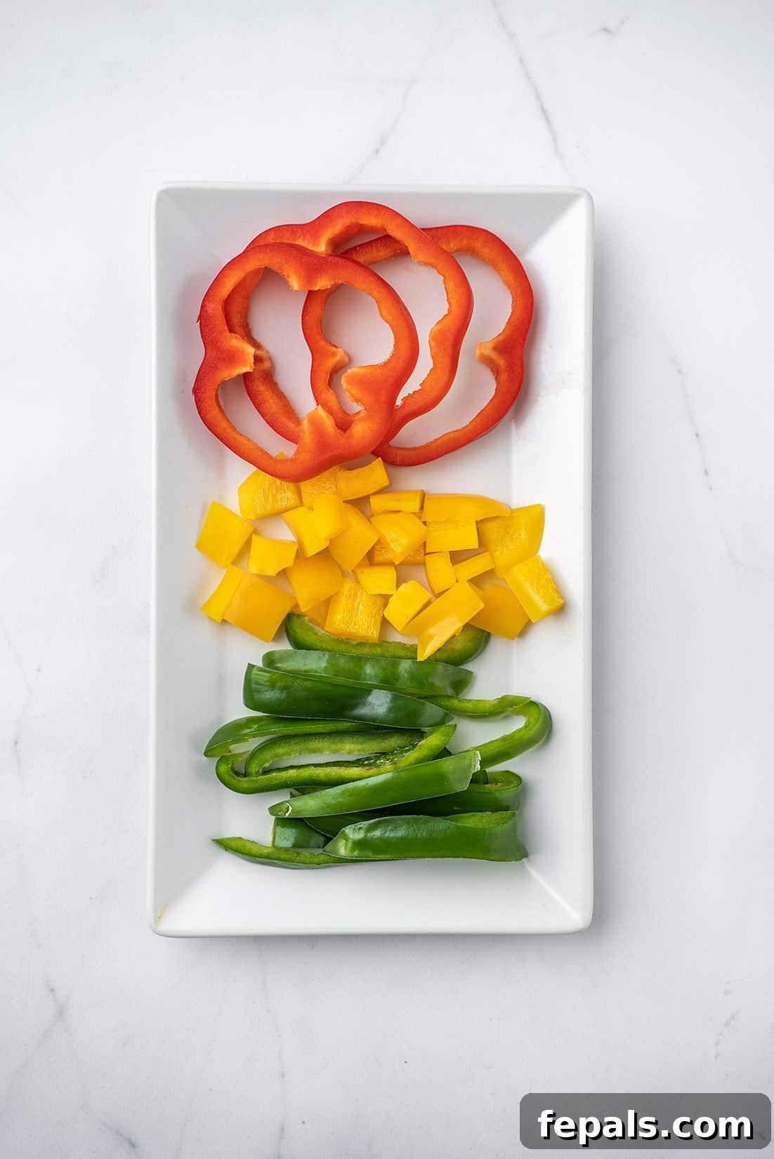 Master Bell Pepper Cutting Three Ways 22 A pristine white plate showcases a colorful medley of perfectly sliced bell peppers, demonstrating their versatility.