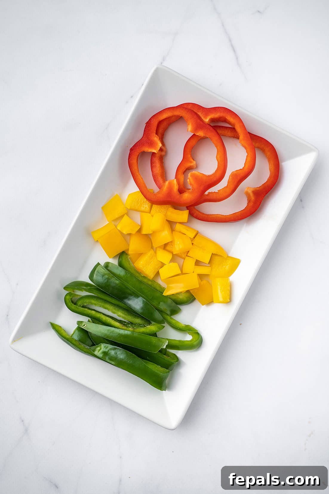 Master Bell Pepper Cutting Three Ways 24 Three types of perfectly sliced bell peppers (julienned, diced, and rings) artfully arranged on a clean white plate.