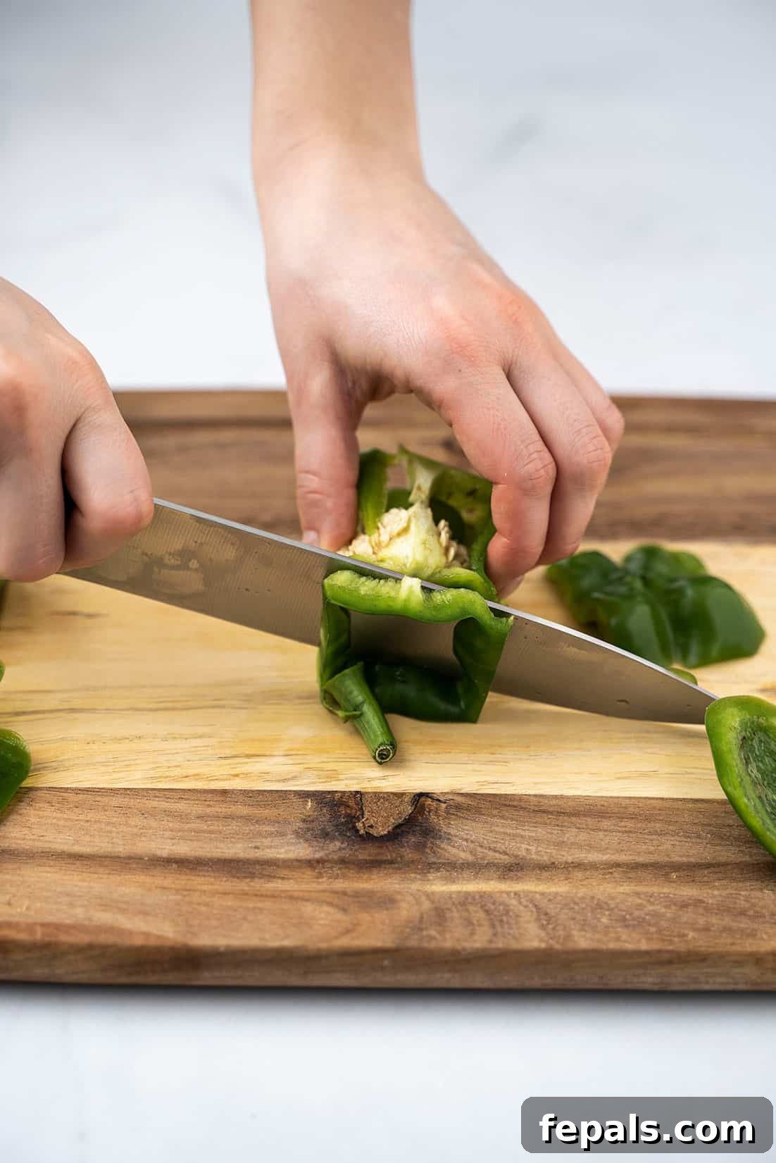Master Bell Pepper Cutting Three Ways 8 Precisely cutting the top section of a bell pepper, separating the stem and inner core.