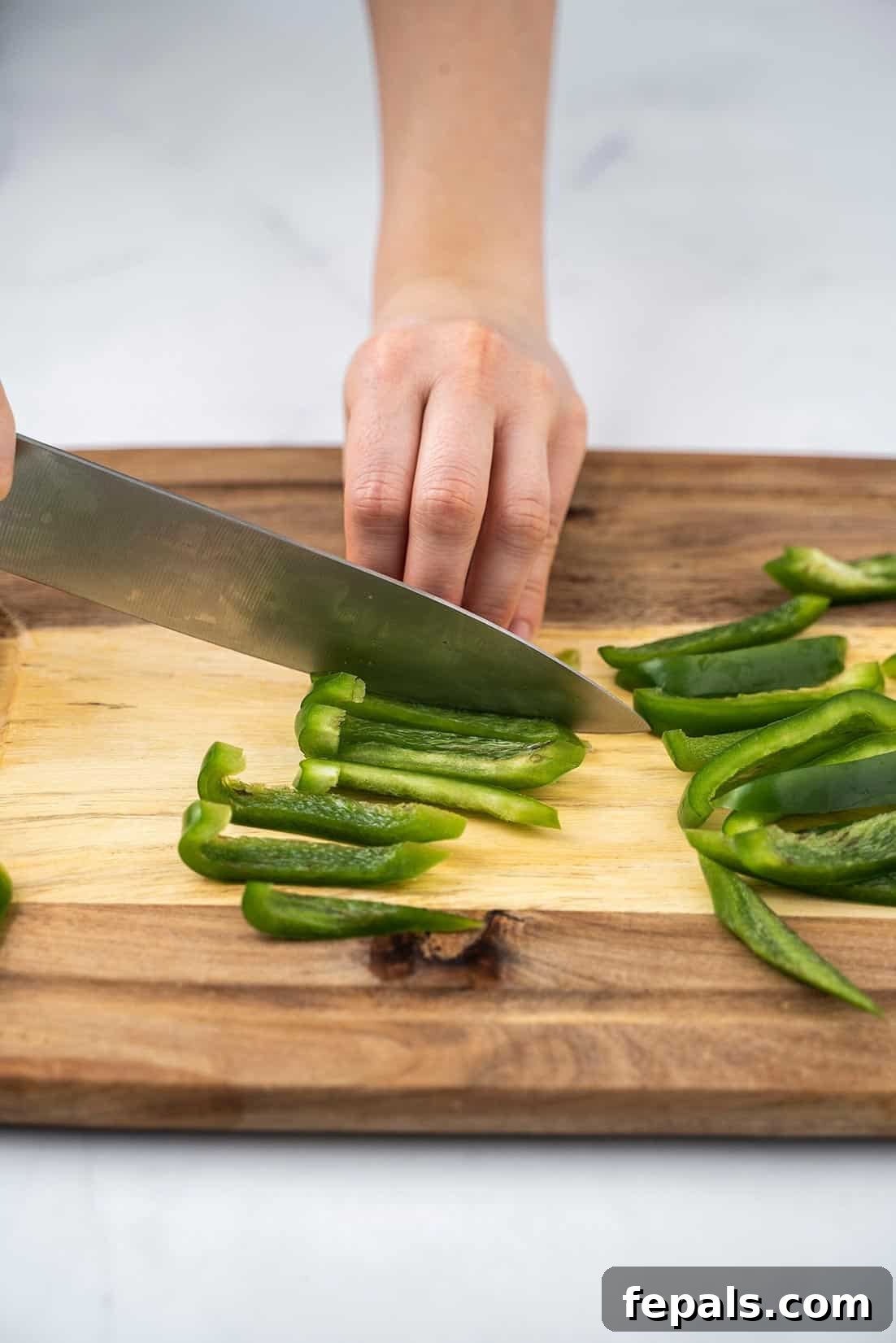 Master Bell Pepper Cutting Three Ways 10 A collection of perfectly cut vertical bell pepper slices, showcasing uniform thickness and clean edges.