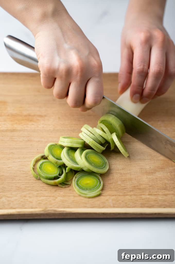 Mastering Leek Slicing 9 Leek being sliced in circular slices on a cutting board.
