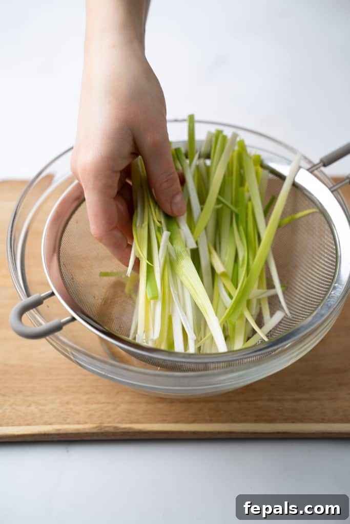 Mastering Leek Slicing 12 Sliced leeks placed in a mesh strainer.