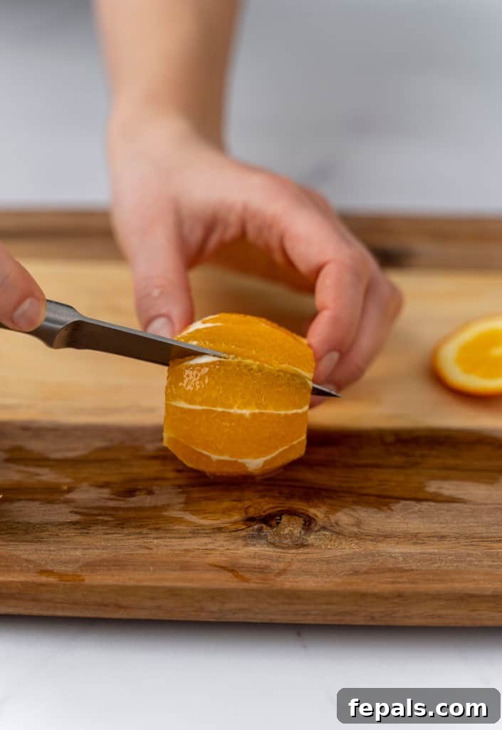 Knife slicing a segment of orange, carefully separating it from the membrane.