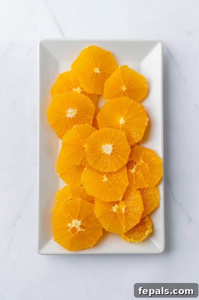 Overhead view of slices of oranges on a white platter, showcasing their vibrant color and freshness.