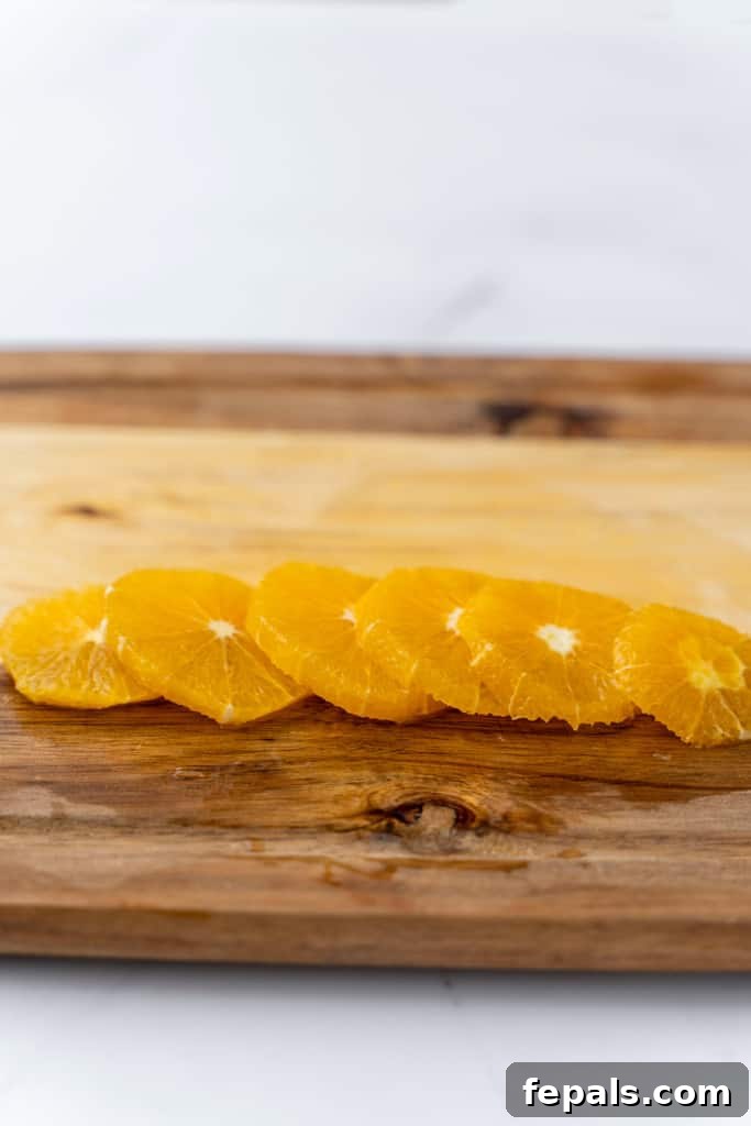 Multiple slices of orange, perfectly laid on a cutting board, ready for use.