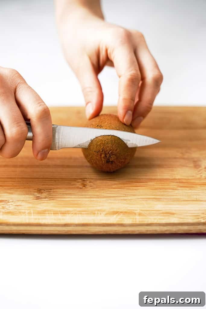 Effortless Kiwi Cutting Techniques 4 Kiwi being cut on a cutting board.