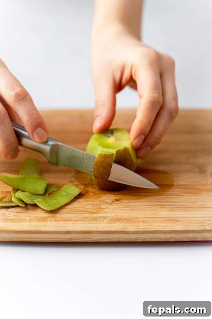 Effortless Kiwi Cutting Techniques 6 A kiwi with the skin being cut off.