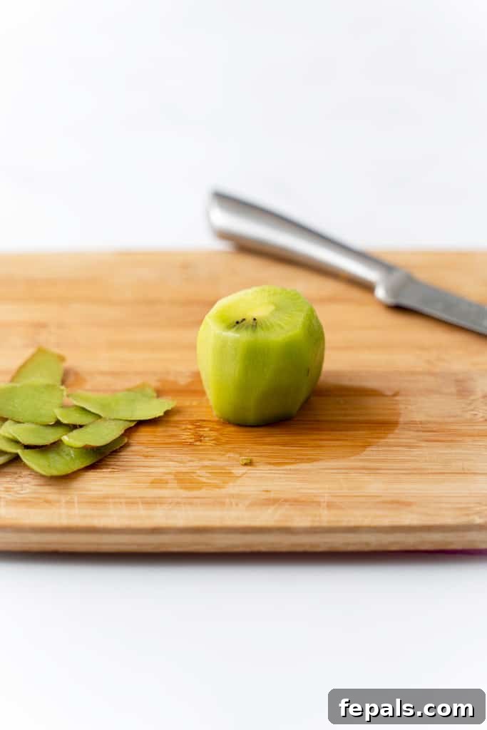 Effortless Kiwi Cutting Techniques 7 A peeled kiwi on a cutting board.