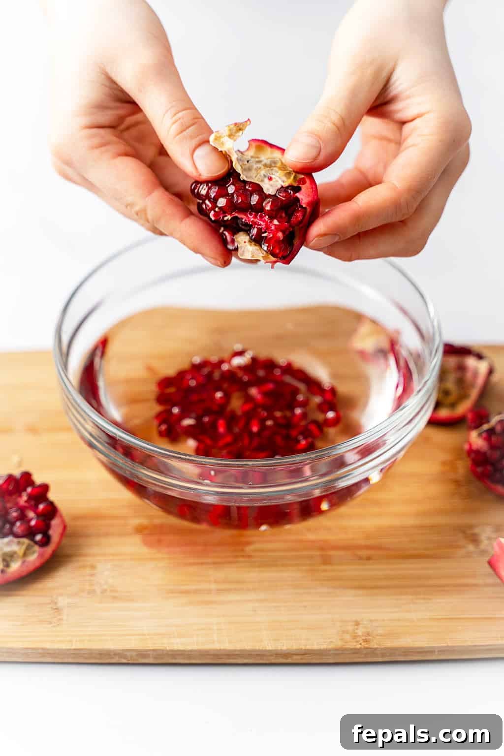 How to Cut a Pomegranate Deseeding a pomegranate by hand over a bowl of water to collect the arils.