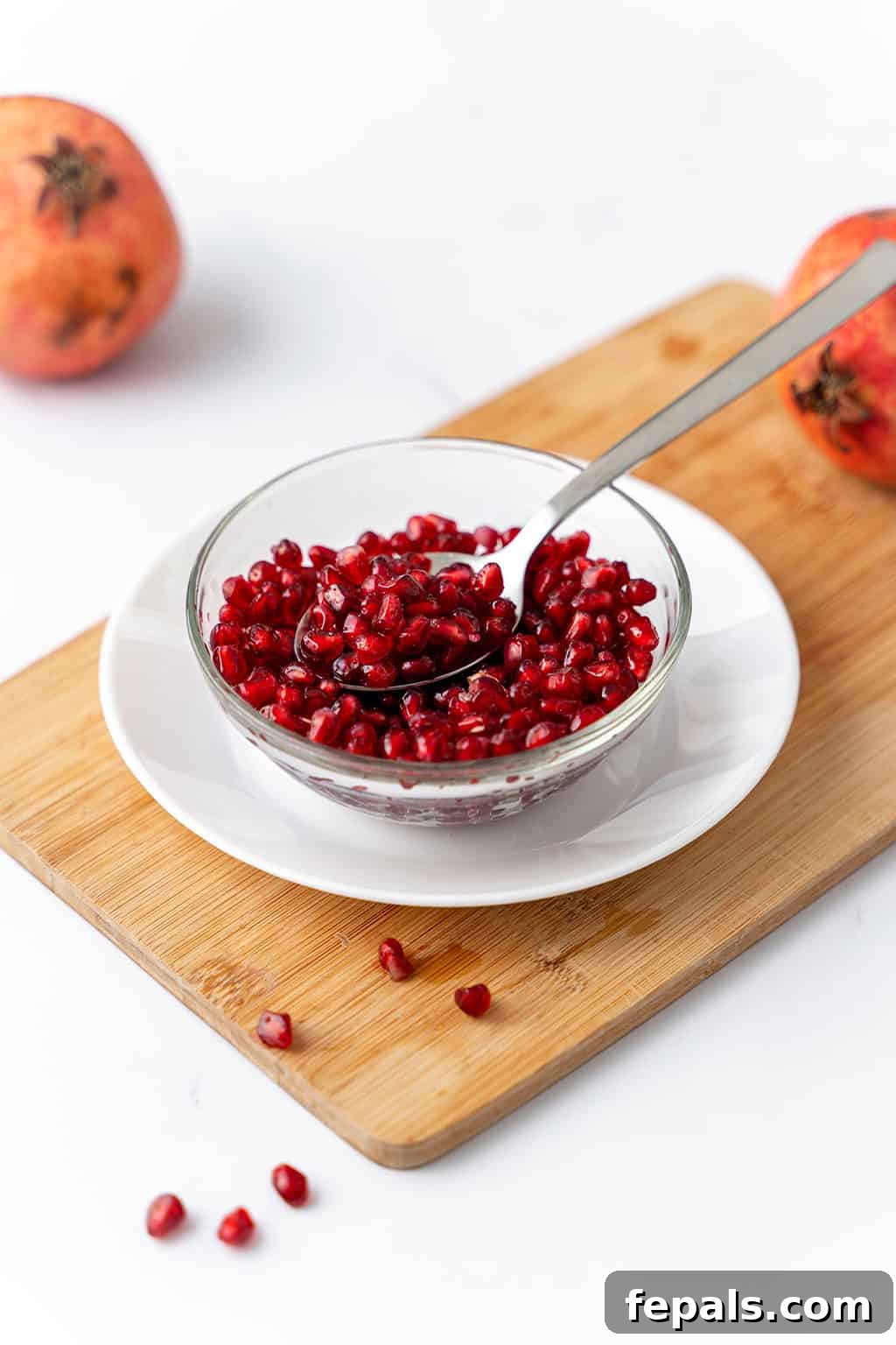 How to Cut a Pomegranate A bowl generously filled with freshly deseeded pomegranate arils, with a spoon resting inside.