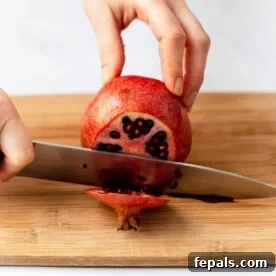 side shot of knife slicing pomegranate