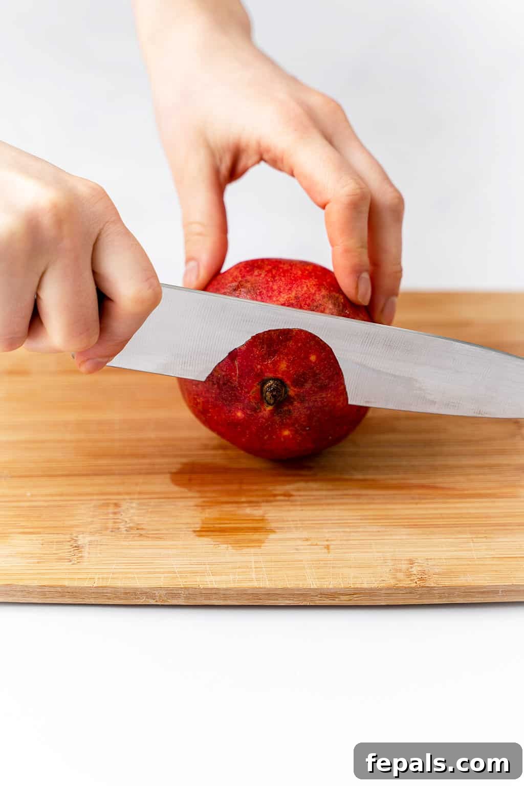 How to Cut a Pomegranate A sharp knife making an additional slice on the bottom end of the pomegranate.