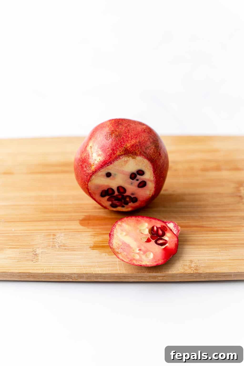 How to Cut a Pomegranate (Easy) A whole pomegranate with its skin intact, illustrating the scoring process.