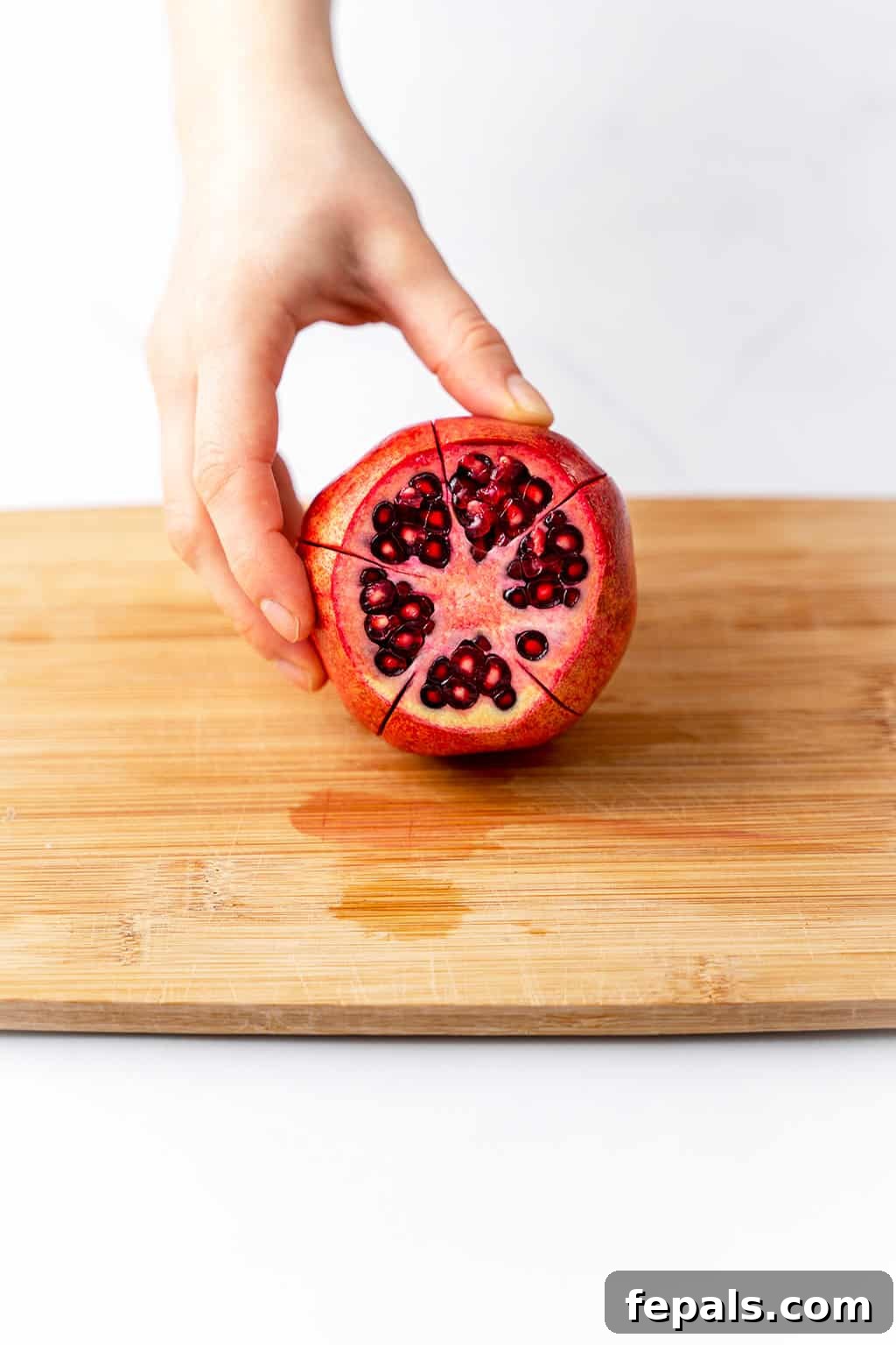How to Cut a Pomegranate A single pomegranate scored into five even segments, ready for opening.