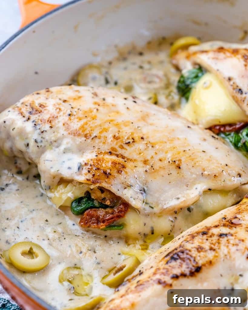 Tuscan Countryside Stuffed Chicken 6 Side view of a luscious Tuscan stuffed chicken breast resting in a vibrant creamy sauce within an orange skillet, ready to be served.