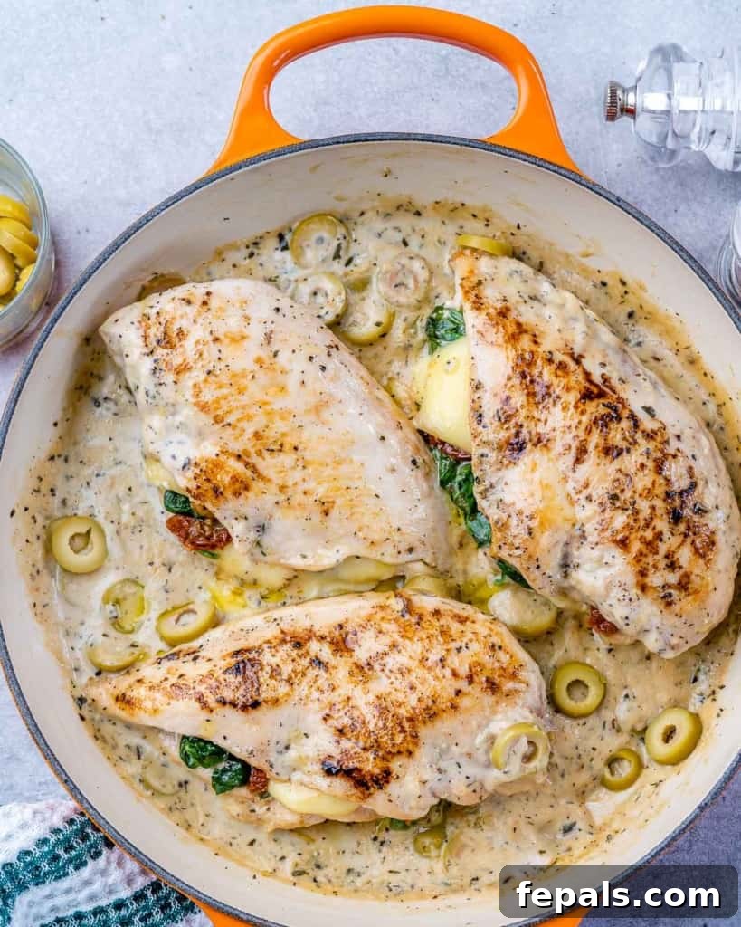 Tuscan Countryside Stuffed Chicken 7 Top-down view of golden-brown Tuscan stuffed chicken breasts bathed in a rich, creamy sauce in an orange pan, garnished with herbs.